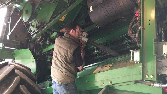 Робочий очищає комбайн ручної бензинової повітродувкою