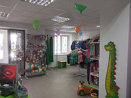 На этом фото мы видим вход в магазин и передвижной "краб" белого цвета для одежды.