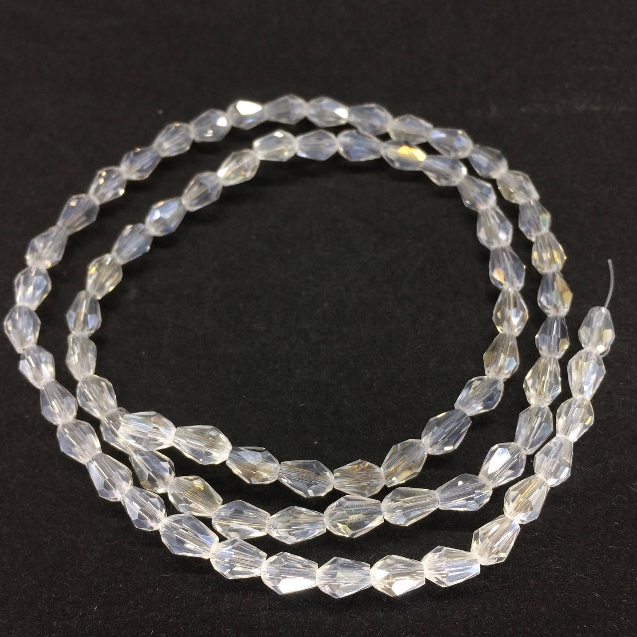 

Бусины на нитке Стекло капля 4*6мм цвет белый прозрачный с переливом (~72 бусины на нитке)