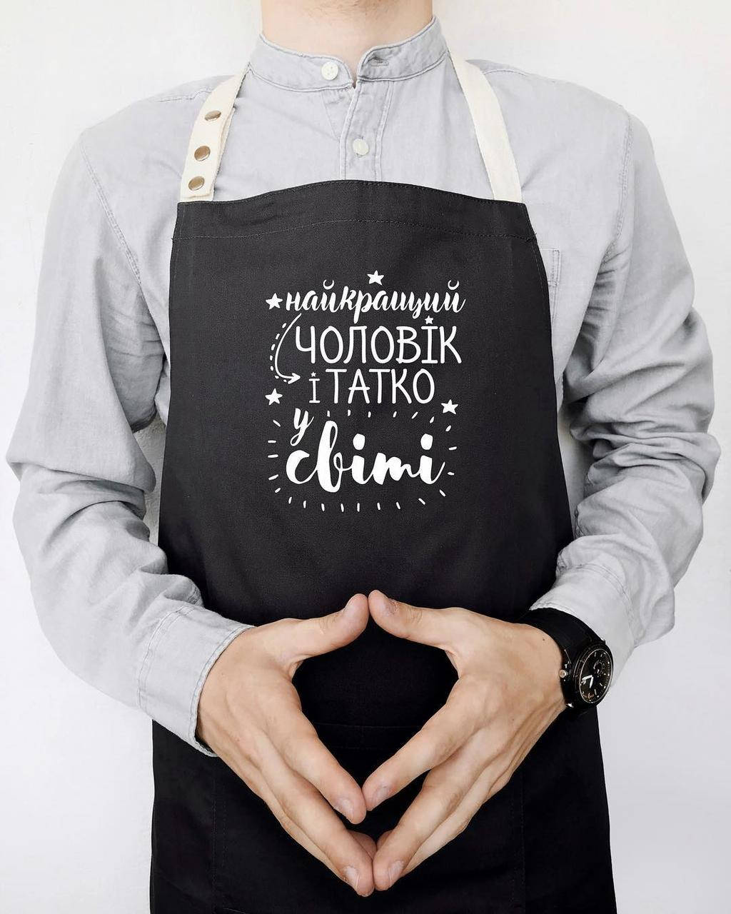 

Мужской фартук для кухни с прикольной надписью "Найкращий чоловік и татко у світі" черный