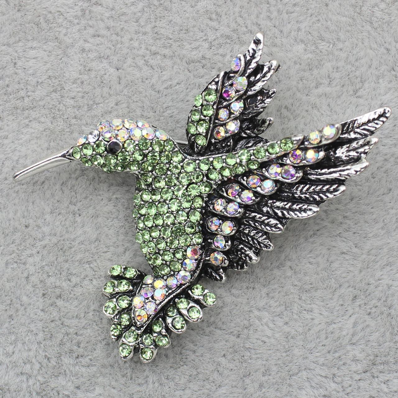 

Брошка металлическая серебристая Колибри со светло-зелеными и переливающимися камнями размер изделия 50х50 мм
