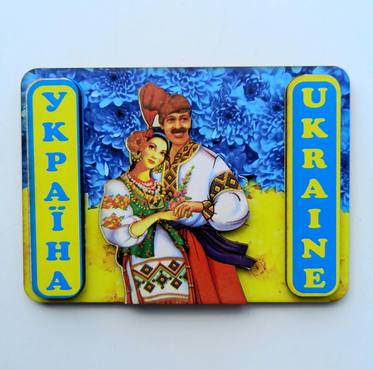 

Магнит , Козак и козака на фоне флага Украины . Надпись Україна , Ukraine .