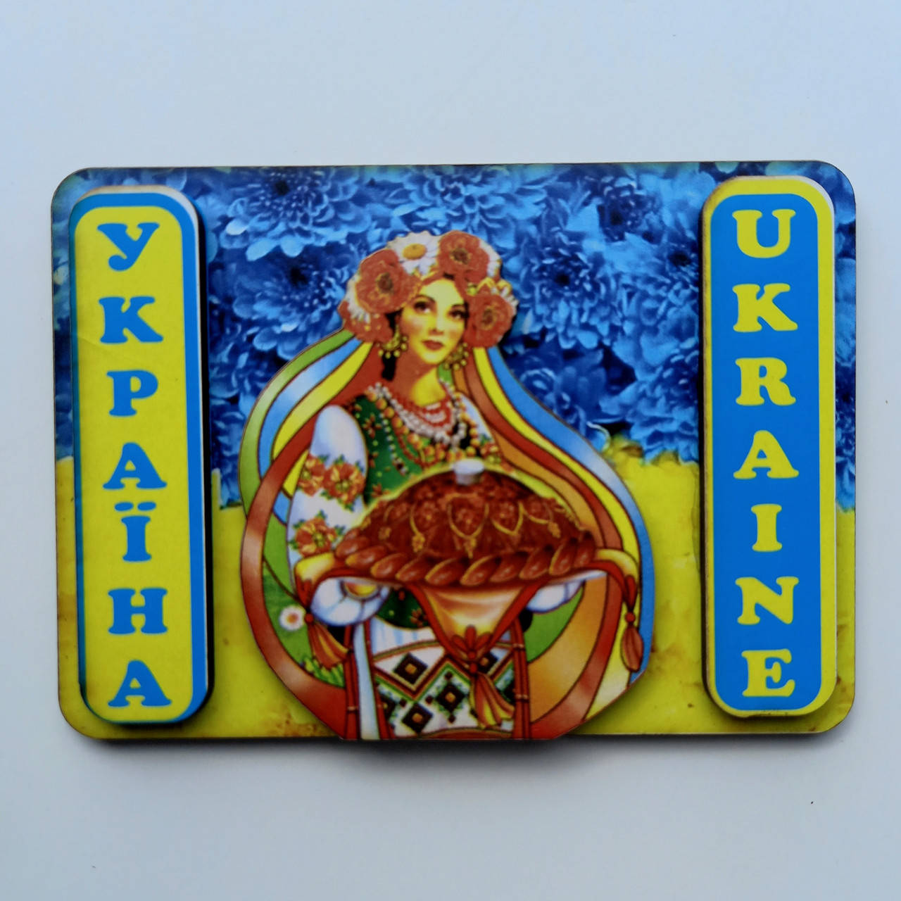 

Магнит , Украинка с короваем на фоне флага Украины . Надпись Україна , Ukraine .
