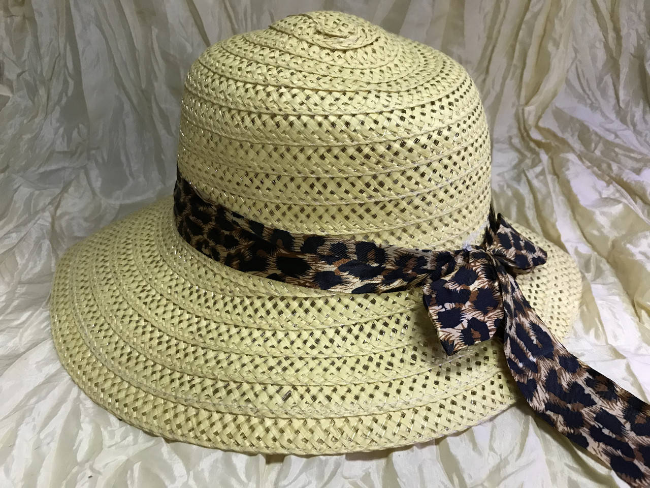 

Летняя бежевая шляпка из соломки украшена леопардовой лентой с бантом
